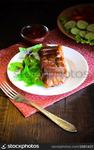 Grilled beef steak with salad and souce on wooden table. Grilled beef steak with salad and souce on wooden table at white plate. Salad with tomatoes and cucumbers and souce barbecue. Leafs of basil as decoration.