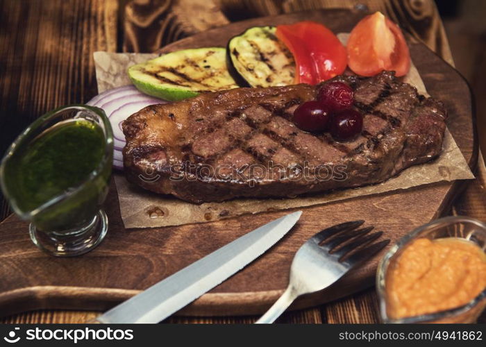 grilled beef steak with sauce and vegetables. grilled beef steak