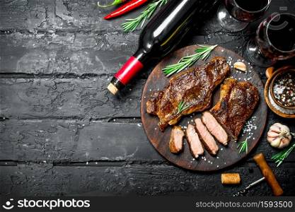 Grilled beef steaks with herbs and red wine. On a black rustic background.. Grilled beef steaks with herbs and red wine.