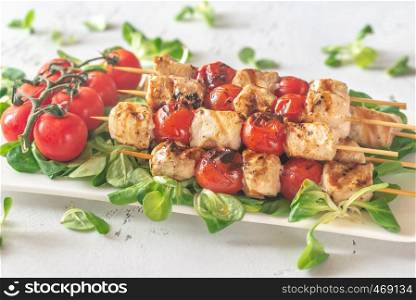 Grilled chicken and cherry tomato skewers on the white plate