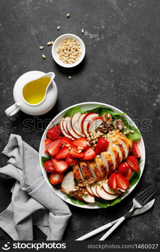 Grilled chicken breast and strawberry salad with red apples, fresh spinach and nuts