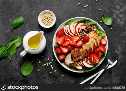 Grilled chicken breast and strawberry salad with red apples, fresh spinach and nuts