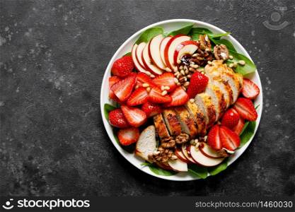 Grilled chicken breast and strawberry salad with red apples, fresh spinach and nuts