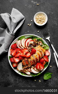 Grilled chicken breast and strawberry salad with red apples, fresh spinach and nuts