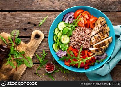 Grilled chicken breast. Fried chicken fillet and fresh vegetable salad of tomatoes, cucumbers, pepper, lettuce and arugula leaves. Chicken meat with salad. Healthy food. Flat lay. Top view. Wooden background