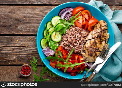 Grilled chicken breast. Fried chicken fillet and fresh vegetable salad of tomatoes, cucumbers, pepper, lettuce and arugula leaves. Chicken meat with salad. Healthy food. Flat lay. Top view. Wooden background