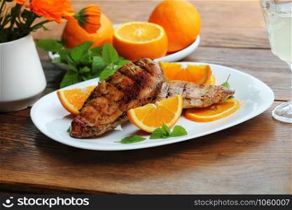 Grilled chicken breast with orange on wooden table. Grilled chicken breast with orange