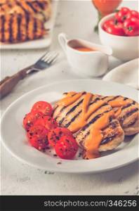 Grilled chicken breast with sauce, chilli flakes and cherry tomatoes