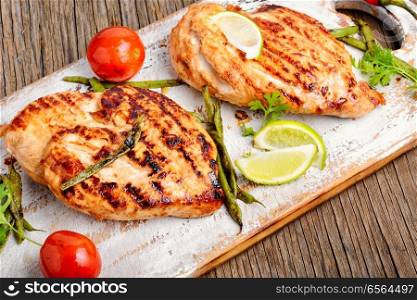 Grilled chicken breast with spices on kitchen board. Roast chicken breast with lime