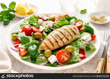 Grilled chicken fillet and fresh green leafy vegetable salad with tomatoes, red onion, olives and feta cheese. Healthy food. Ketogenic lunch