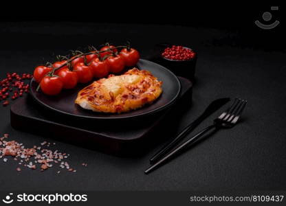 Grilled chicken fillet in the form of a steak with tomatoes, pineapple and cheese on a dark concrete background