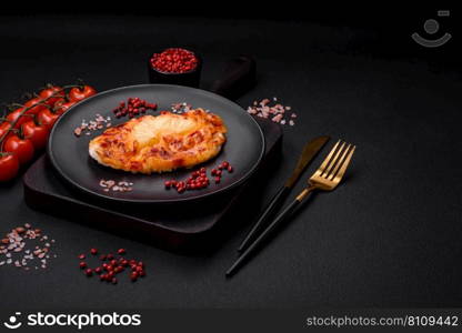 Grilled chicken fillet in the form of a steak with tomatoes, pineapple and cheese on a dark concrete background