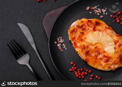 Grilled chicken fillet in the form of a steak with tomatoes, pineapple and cheese on a dark concrete background