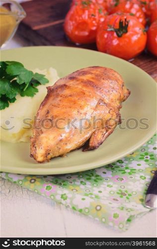 Grilled chicken fillet with mashed potatoes and grilled tomatoes. Rustic style.. Grilled chicken fillet with mashed potatoes and grilled tomatoes. Rustic style. Vintage fork and white wooden table.