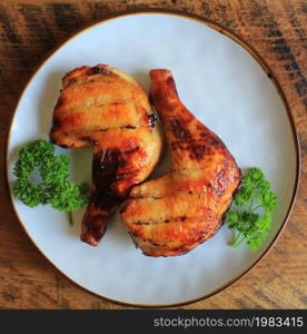 Grilled chicken leg quarters with crispy golden brown skin, lemon, parsley on white plate on dark wooden boards. Food background. Top view .. Grilled chicken leg quarters with crispy golden brown skin, lemon, parsley on white plate on dark wooden boards. Food background. Top view