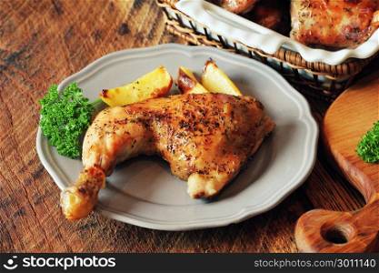 Grilled chicken leg with potato for garnish. Wooden background.. Grilled chicken legs c with potato for garnish. Top view. Wooden background.
