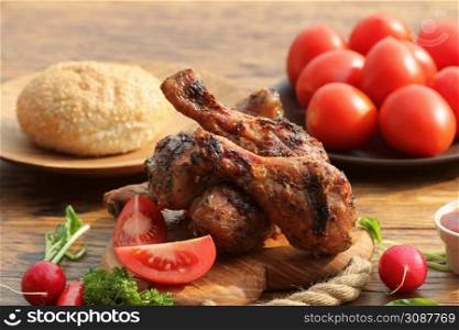 Grilled chicken legs on cutting board.Rustic dinner background.. Grilled chicken legs on cutting board.Rustic dinner background