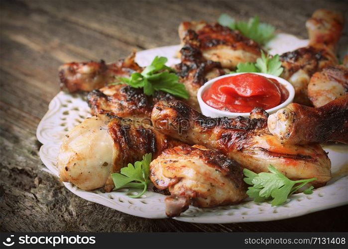 Grilled chicken legs on wooden table served on white plate with coriander .. Grilled chicken legs on wooden table served on white plate with coriander