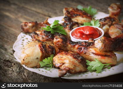 Grilled chicken legs on wooden table served on white plate with coriander .. Grilled chicken legs on wooden table served on white plate with coriander