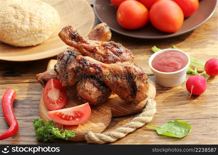 Grilled chicken legs with herbs on cutting board. Dinner background.. Grilled chicken legs on cutting board.Rustic dinner background.