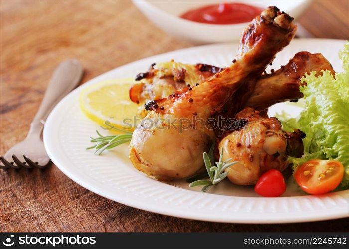 Grilled chicken legs with mustard on wooden table served on white plate with rosemary. BBQ dinner background .. Grilled chicken legs with mustard on wooden table served on white plate with rosemary. BBQ dinner background