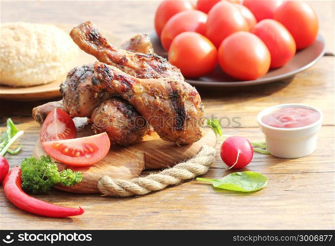 Grilled chicken legs with vegetables on cutting board.. Grilled chicken legs with herbs on cutting board. Dinner background.