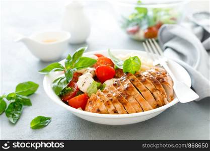 Grilled chicken lunch bowl with orange juice dressing, pasta and caprese salad