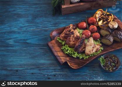 Grilled chicken meat. Grilled chicken meat with vegetable on a blue wooden background