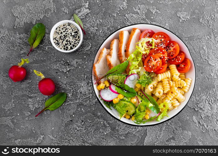 Grilled chicken meat with fresh vegetable salad of tomato, cucumber, radish, lettuce, chard leaves, corn and pasta. Healthy lunch menu. Top view