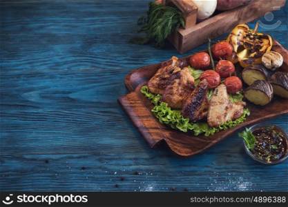 Grilled chicken meat with vegetable on a blue wooden background. Grilled chicken meat