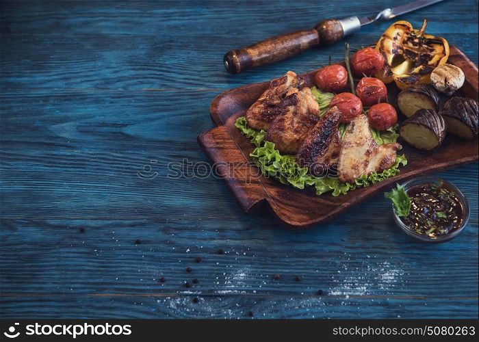 Grilled chicken meat with vegetable on a blue wooden background. Grilled chicken meat