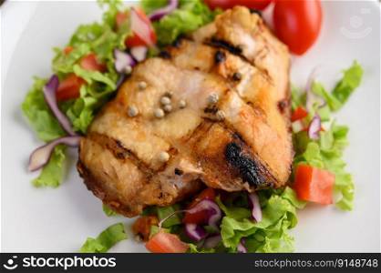 Grilled chicken on a white plate with a salad of tomatoes, carrots and chilies cut into pieces. Selective focus.