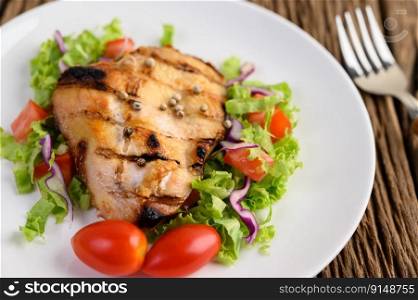 Grilled chicken on a white plate with a salad of tomatoes, carrots and chilies cut into pieces. Selective focus.