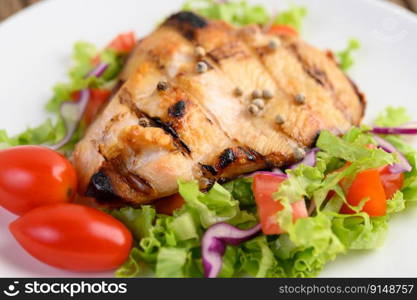 Grilled chicken on a white plate with a salad of tomatoes, carrots and chilies cut into pieces. Selective focus.