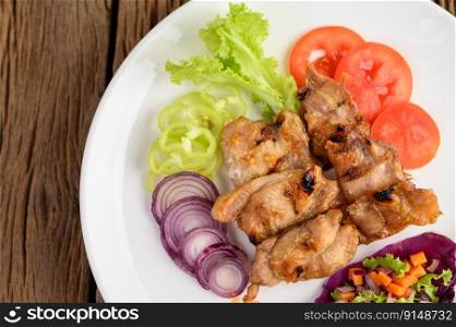 Grilled chicken on a white plate with a salad, tomatoes, red onion, and chilies cut into pieces on wooden table.Top view.