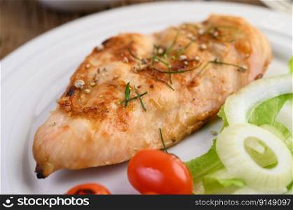 Grilled chicken on a white plate with tomatoes, salad and onion.