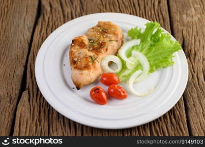 Grilled chicken on a white plate with tomatoes, salad and onion.