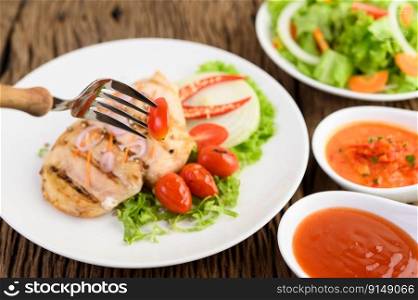 Grilled chicken on a white plate with tomatoes, salad, onion, chili and sauce. Select tomato on skewer fork.