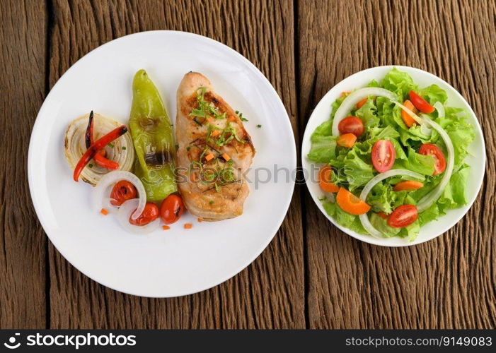 Grilled chicken on a white plate with tomatoes, salad, onion, chili and sauce.