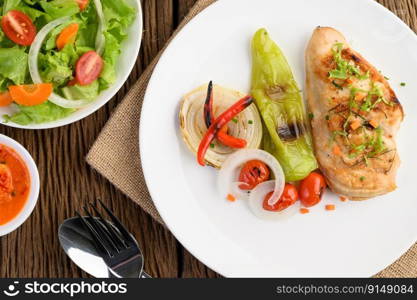 Grilled chicken on a white plate with tomatoes, salad, onion, chili and sauce.