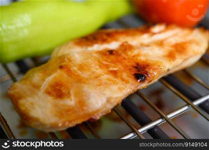 Grilled chicken on an electric grill with paprika and tomato.