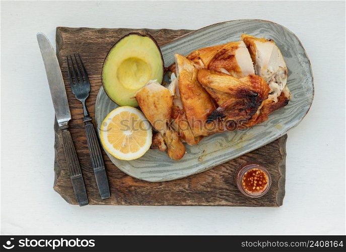 Grilled chicken or Roasted chicken with Avocado and Lemon cut in half serve with Sweet chili sauce. Healthy thai food concept, View from above, Selective focus.