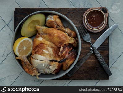 Grilled chicken or Roasted chicken with Avocado and Lemon cut in half serve with Sweet chili sauce. Healthy thai food concept, View from above, Selective focus.