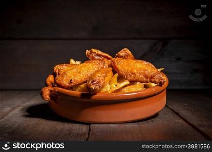 Grilled chicken wings on a rustic plate on wooden table. High quality photography. Grilled chicken wings on a rustic plate on wooden table.