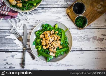 Grilled chicken with spinach,arugula and peas on rustic wooden background