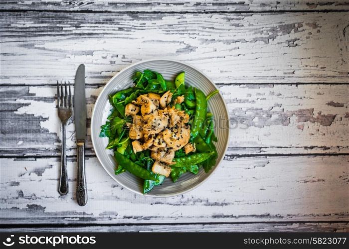 Grilled chicken with spinach,arugula and peas on rustic wooden background