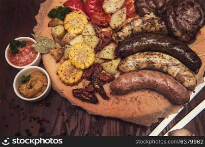 Grilled different meat and fish sausages with vegetables and spices on wooden background. Grilled sausages with vegetables