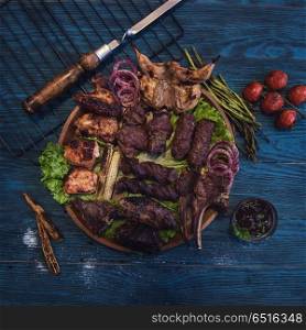 Grilled different meat set. Grilled different meat set with vegetable on a blue wooden background