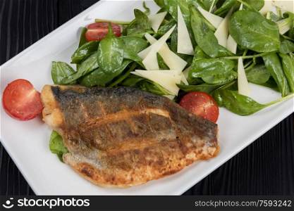 Grilled Dorado fish fillet with spinach, tomato and cheese. Grilled Dorado fish fillet