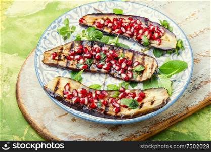 Grilled eggplant cooked with pomegranate.Roasted vegetables on plate. Half an eggplant grill